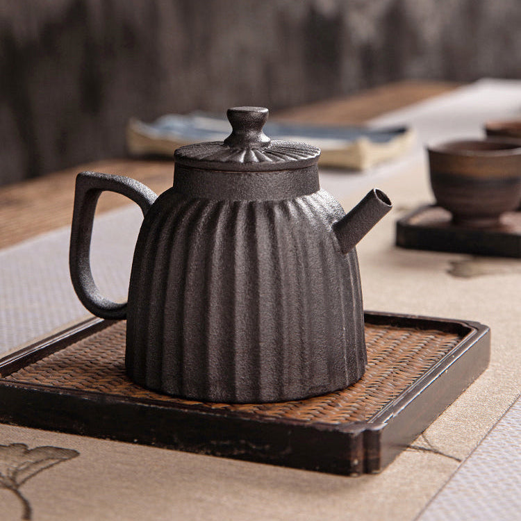 Black ceramic teapot on a wooden tray 